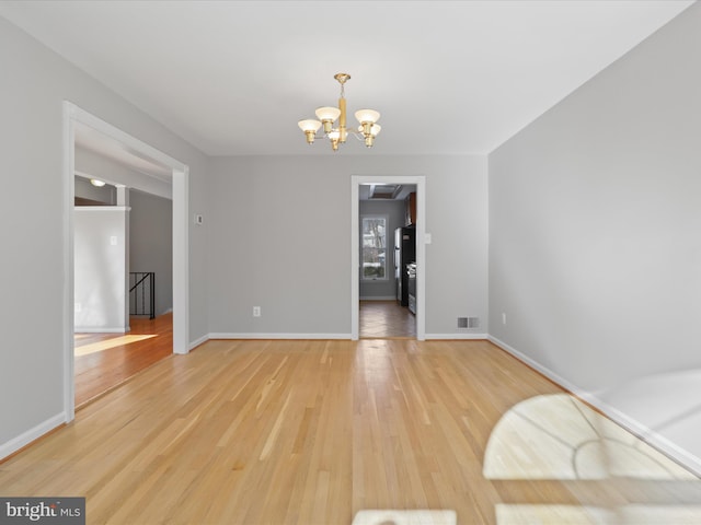 unfurnished dining area featuring a notable chandelier and light hardwood / wood-style floors