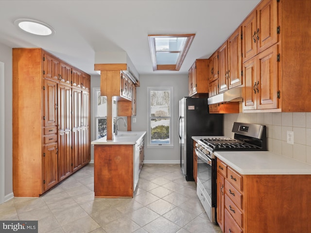 kitchen with stainless steel range with gas cooktop, sink, light tile patterned floors, and backsplash