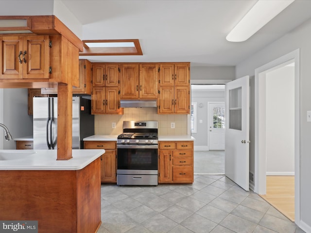 kitchen with tasteful backsplash, appliances with stainless steel finishes, light tile patterned flooring, and sink