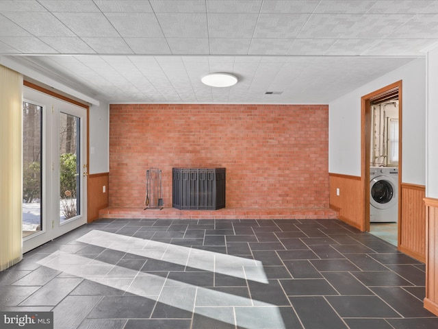 unfurnished living room featuring wooden walls and washer / dryer