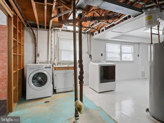 washroom featuring water heater, sink, cabinets, and independent washer and dryer