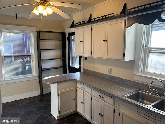 kitchen with white cabinets, a healthy amount of sunlight, kitchen peninsula, and sink