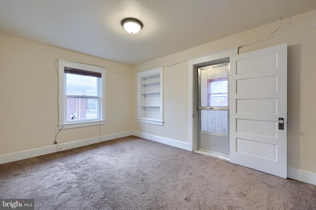 carpeted empty room featuring built in shelves