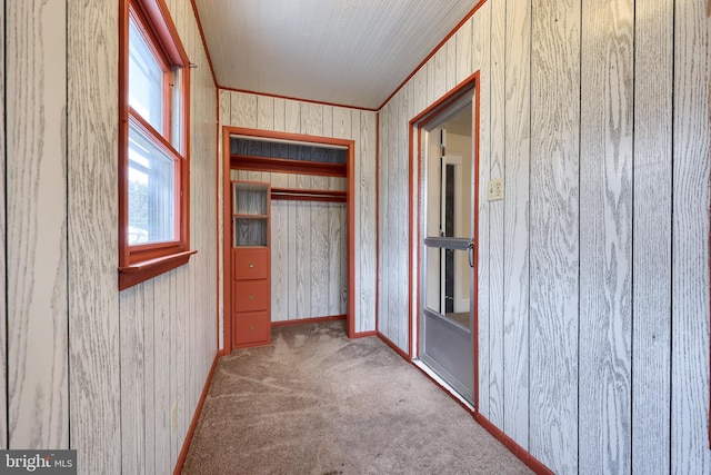 corridor featuring crown molding, light carpet, and wood walls