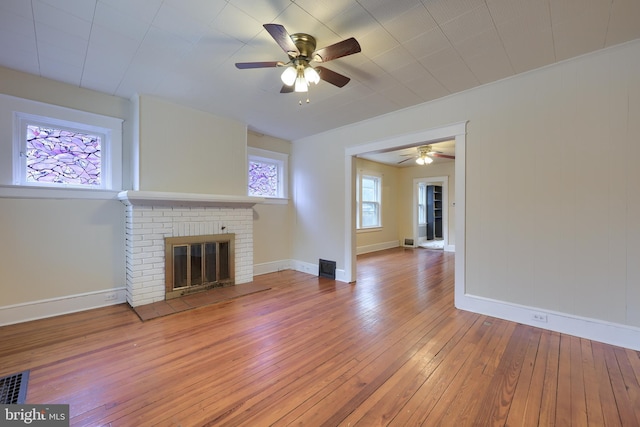 unfurnished living room featuring hardwood / wood-style floors, a brick fireplace, and ceiling fan