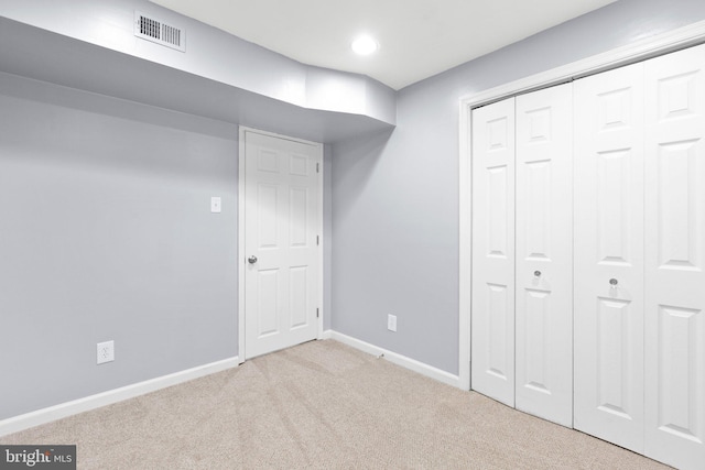 unfurnished bedroom with light colored carpet and a closet