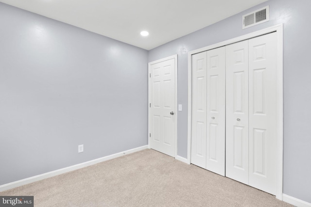 unfurnished bedroom featuring a closet and light carpet