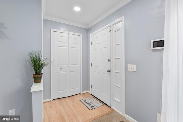 foyer entrance featuring crown molding and light hardwood / wood-style flooring