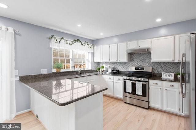 kitchen featuring stainless steel appliances, kitchen peninsula, dark stone counters, and white cabinets