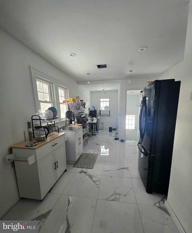 kitchen with white cabinetry, black refrigerator, and sink
