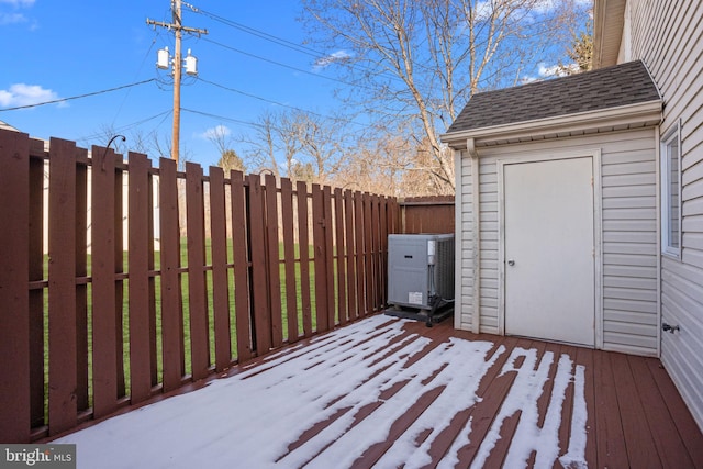 snow covered deck with central AC unit and a shed