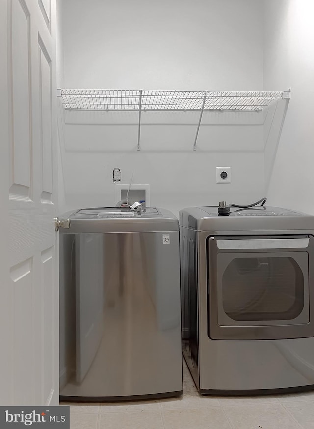 clothes washing area featuring washing machine and dryer and light tile patterned floors