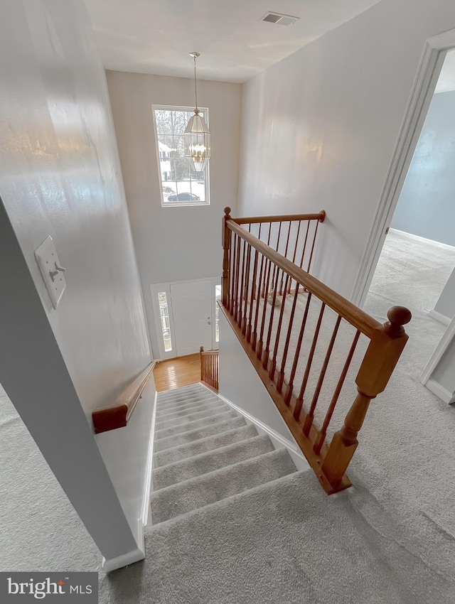 staircase featuring carpet and a notable chandelier