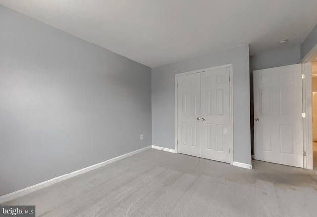 unfurnished bedroom with a closet and light colored carpet