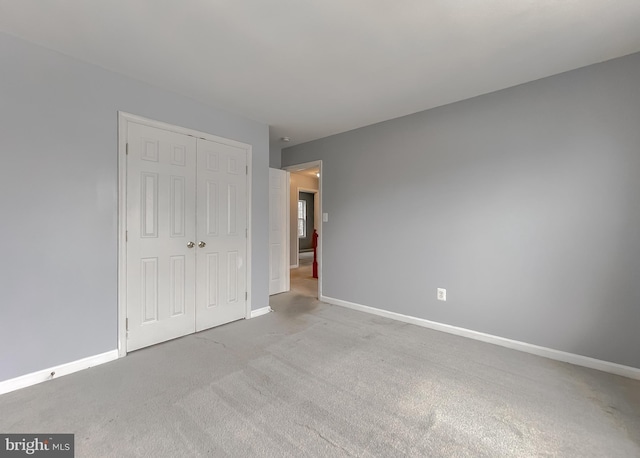 unfurnished bedroom featuring light carpet and a closet