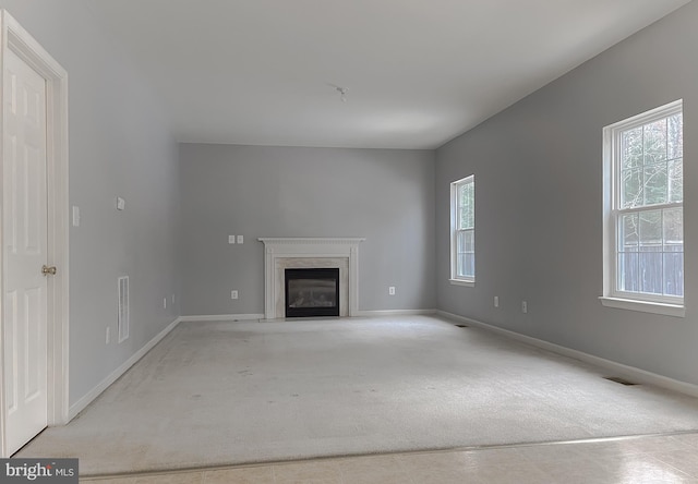 unfurnished living room with light colored carpet and a premium fireplace