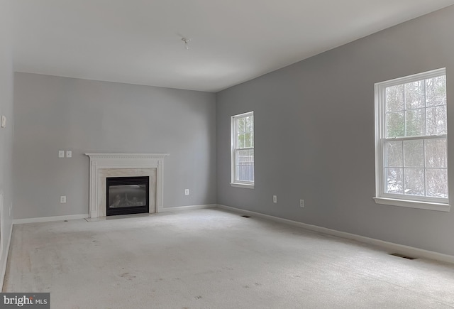 unfurnished living room with light colored carpet and a high end fireplace