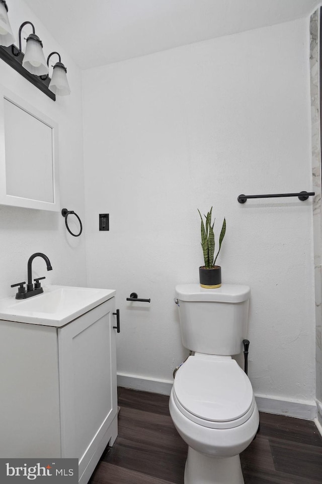 bathroom with hardwood / wood-style floors, vanity, and toilet