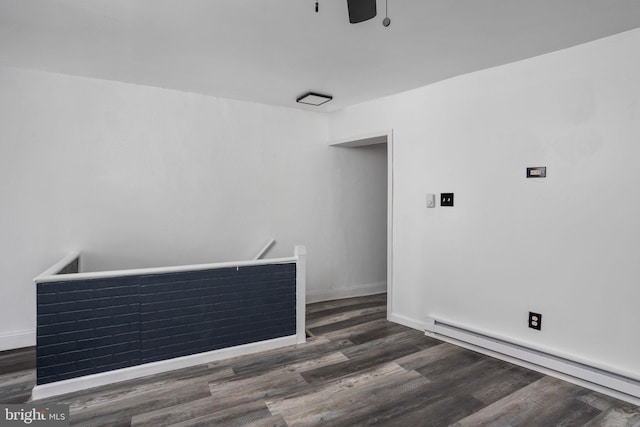 empty room featuring ceiling fan, dark hardwood / wood-style flooring, and a baseboard heating unit