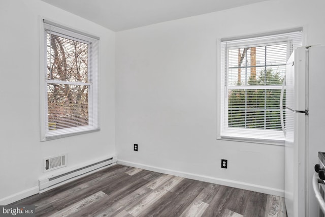 unfurnished room featuring plenty of natural light, dark hardwood / wood-style floors, and a baseboard radiator