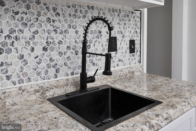 details featuring light stone countertops, white cabinetry, and sink