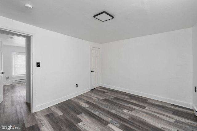 empty room with dark hardwood / wood-style flooring and baseboard heating