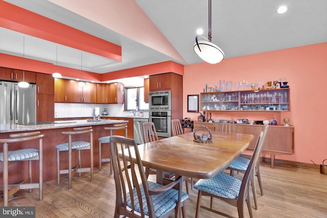 dining room with vaulted ceiling and light hardwood / wood-style flooring