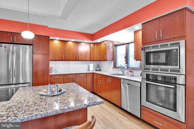 kitchen with decorative light fixtures, light hardwood / wood-style floors, decorative backsplash, appliances with stainless steel finishes, and sink