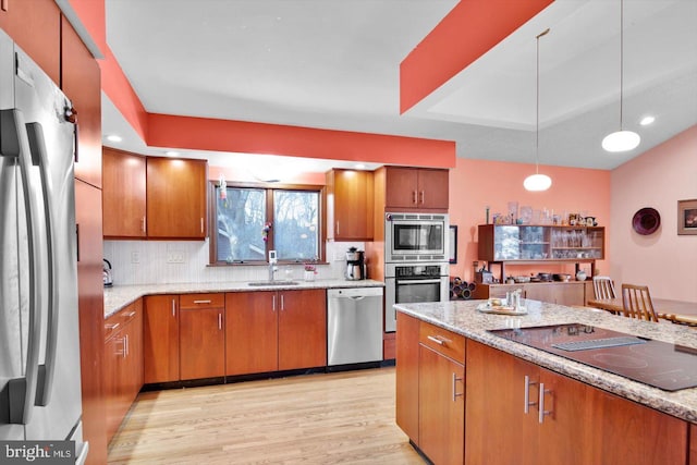 kitchen featuring tasteful backsplash, light hardwood / wood-style flooring, light stone countertops, pendant lighting, and appliances with stainless steel finishes