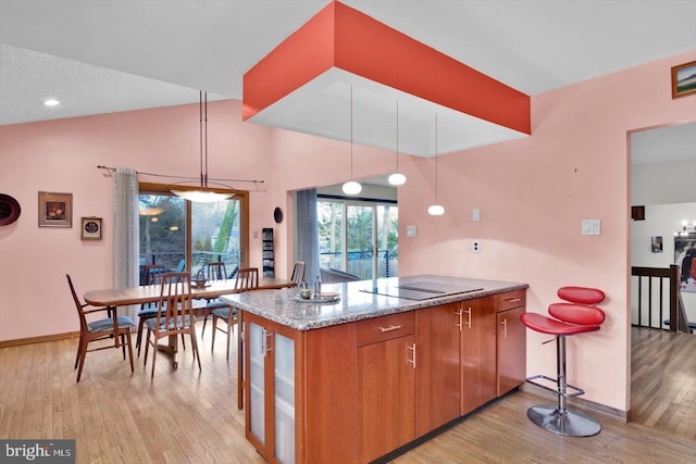 kitchen featuring light hardwood / wood-style floors, black electric stovetop, pendant lighting, and kitchen peninsula