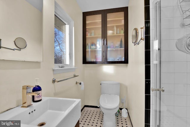 bathroom with sink, a shower with shower door, and toilet