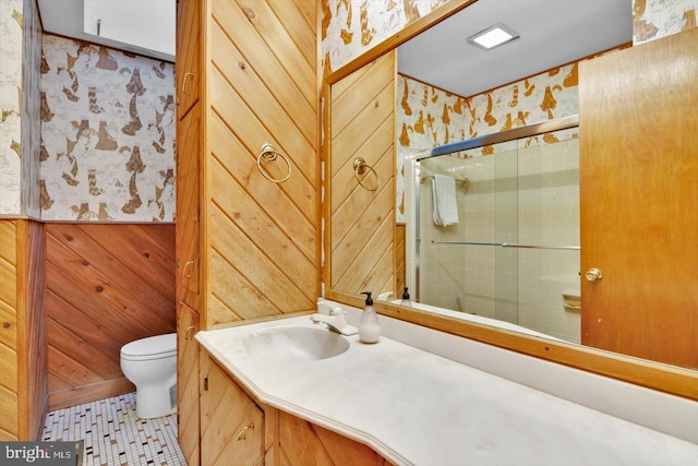 bathroom with wood walls, toilet, vanity, tile patterned floors, and an enclosed shower