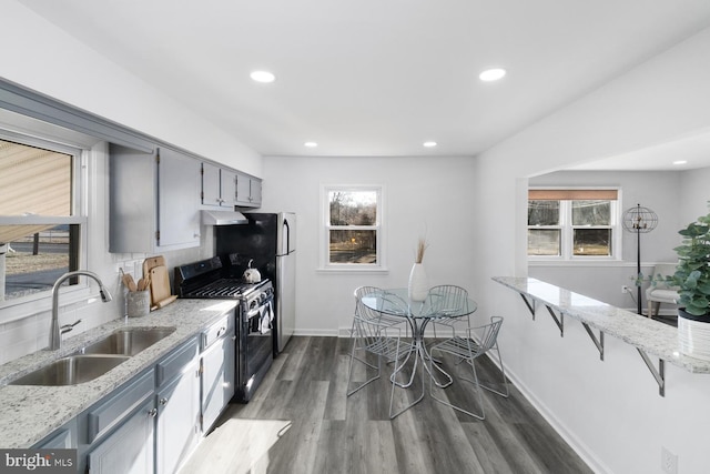 kitchen with sink, light stone counters, range with gas stovetop, dark hardwood / wood-style floors, and gray cabinetry