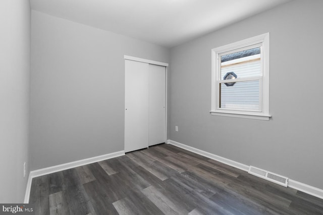 unfurnished bedroom featuring dark wood-type flooring and a closet