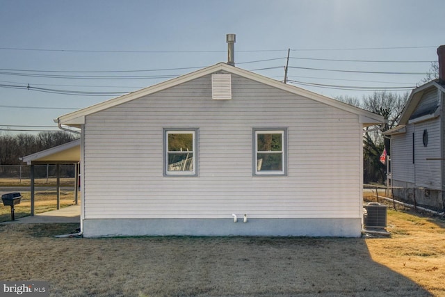 view of side of property with a yard and central AC