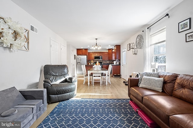 living room with an inviting chandelier and light hardwood / wood-style flooring