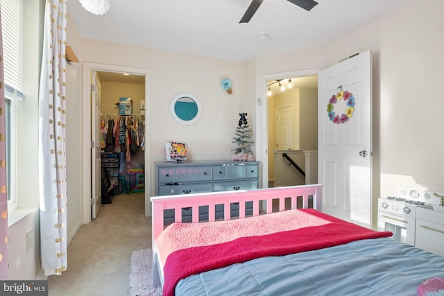 bedroom featuring ceiling fan, a closet, a spacious closet, and light carpet