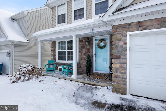 snow covered property entrance featuring a garage