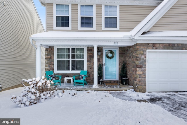 snow covered property entrance with a garage