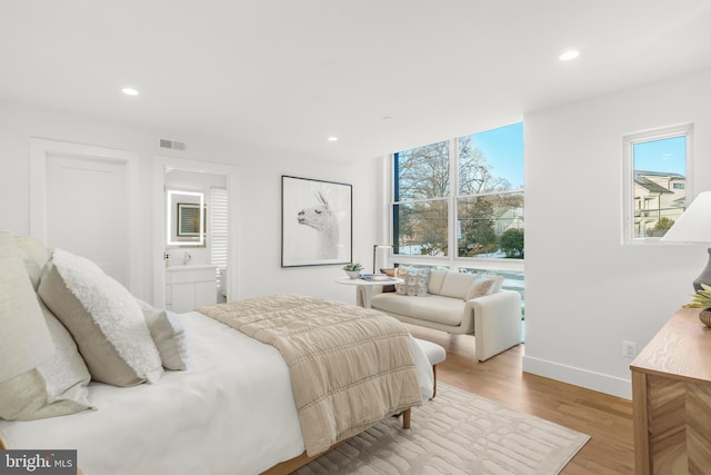 bedroom featuring light hardwood / wood-style flooring and ensuite bath