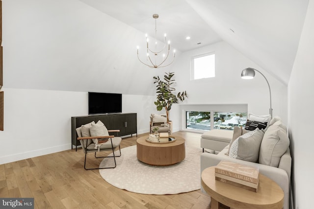 living room featuring light hardwood / wood-style floors, plenty of natural light, a notable chandelier, and vaulted ceiling