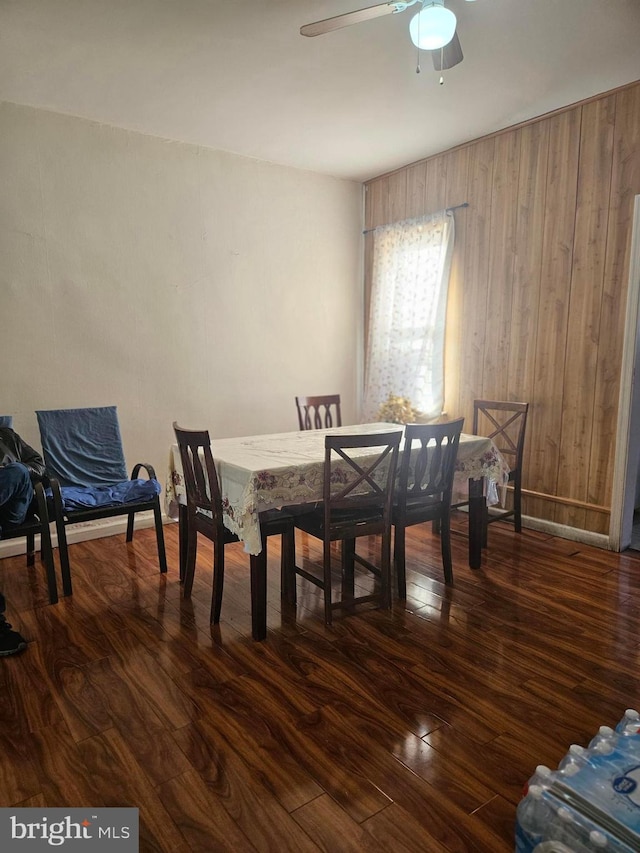 dining area featuring wood walls, ceiling fan, and dark hardwood / wood-style floors