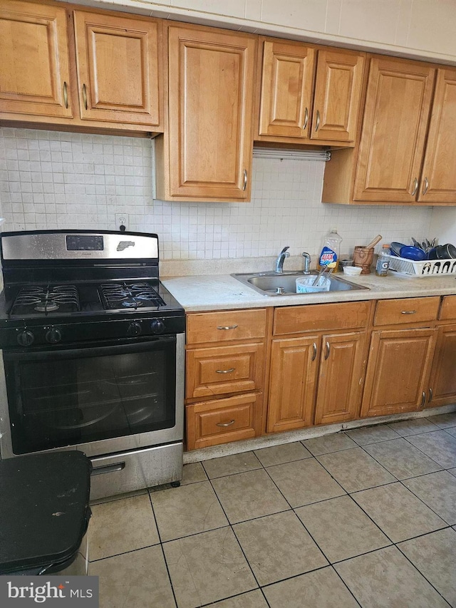 kitchen featuring gas stove, sink, and light tile patterned floors