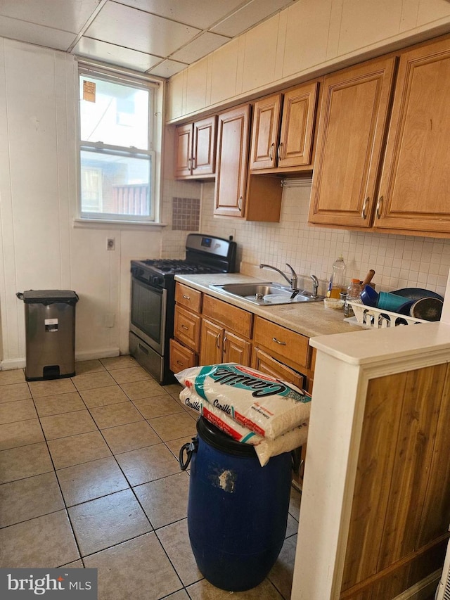 kitchen featuring light tile patterned flooring, sink, and stainless steel gas range