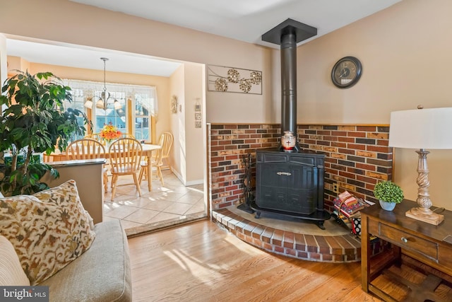 living room with a wood stove, light hardwood / wood-style flooring, and an inviting chandelier