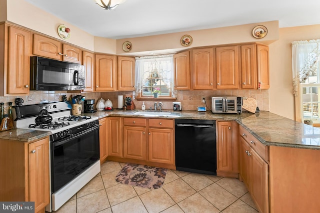 kitchen featuring kitchen peninsula, black appliances, dark stone counters, and sink