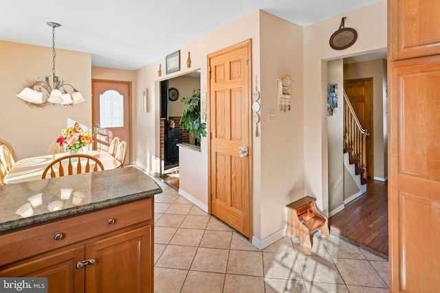 kitchen with hanging light fixtures, a notable chandelier, dark stone counters, and light tile patterned flooring