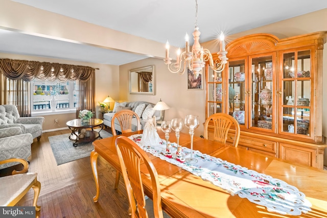 dining space featuring wood-type flooring and an inviting chandelier