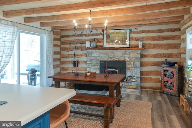 dining space with a notable chandelier, a stone fireplace, wooden walls, wood finished floors, and beamed ceiling