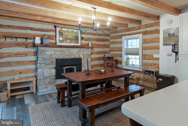 dining room featuring a notable chandelier, beamed ceiling, a fireplace, and wood finished floors